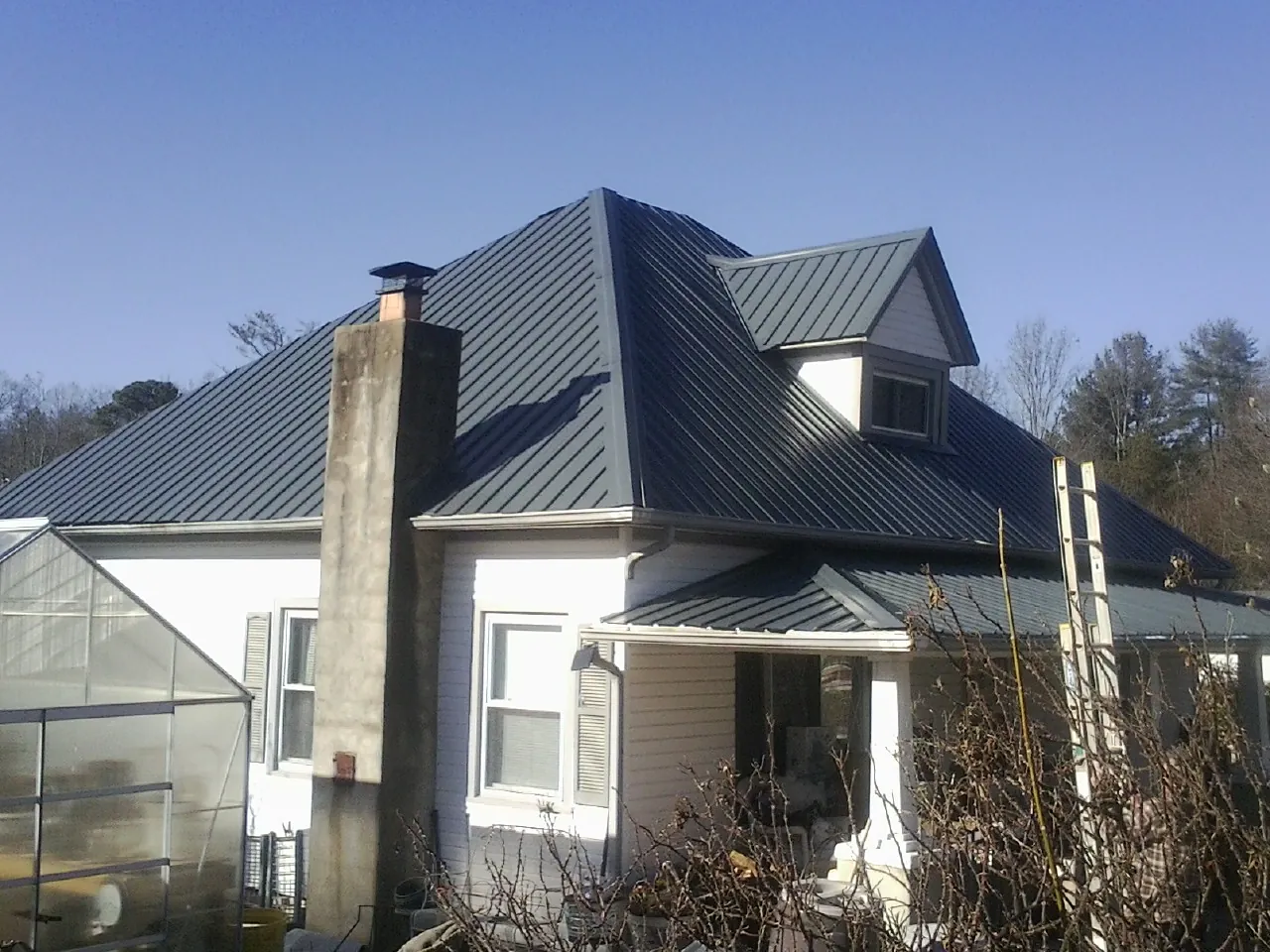 Dark blue standing seam metal roof on a white farmhouse with dormer — Slate & Tile Roof Repair by Roofing Brothers in Malta