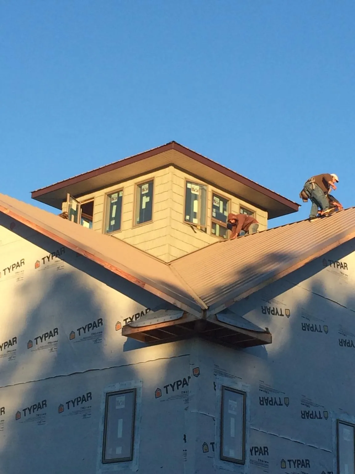 Roofers working around a rooftop cupola on a new metal roof at sunset — Roof Waterproofing in Malta by Roofing Brothers